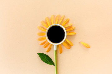 Cup of coffee and flower petals on a beige background. Flat lay, top view