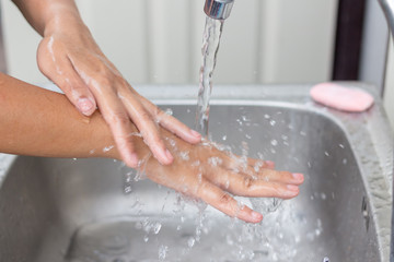 Fototapeta premium woman washing hands in kitchen at home