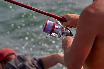 Primer plano de pescador con su caña de carrete pescando en el mar.