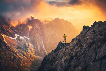 Hiker in beautiful sunset mountains landscape. Alone man on the top of the hill looking to the valley. Sunset sky, edit space for your montage..