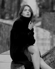 Young brunette woman at the black coat posing at the city