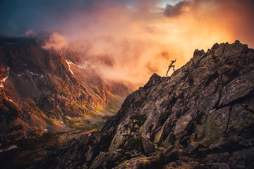 Trail runner in dramatic sunset mountains landscape. Sport photo, orange edit space..