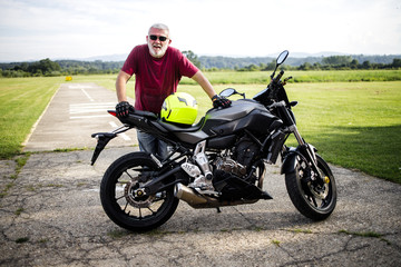 Fototapeta na wymiar A middle-aged man enjoys with his motorcycle