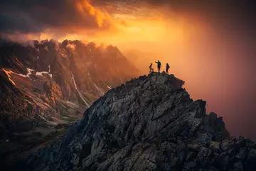Tuinposter Team succes concept foto, vrienden staan samen op de top van de heuvel, over een prachtig berglandschap in gouden zonsonderganglicht, oranje bewerkingsruimte. © kovop58