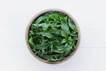 Arugula in a bowl on a white wooden background. Farm fresh rucola leaves.