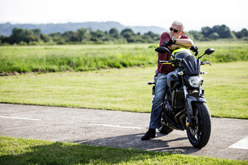 Obraz premium A middle-aged man enjoys with his motorcycle