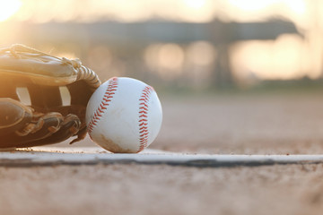 baseball and glove on field during sunset close up, blurred background