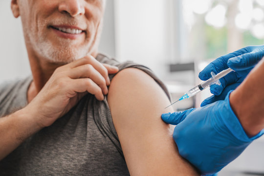 Doctor making injection to senior patient in clinic