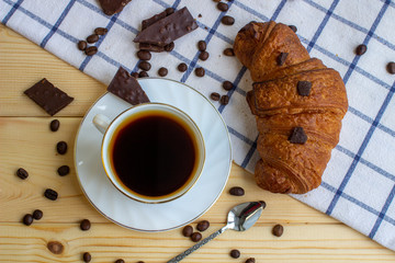 Coffee and a croissant on a wooden background. Visa from above