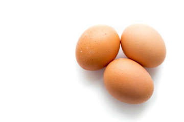 Three large brown chicken eggs on a white background with reflection.