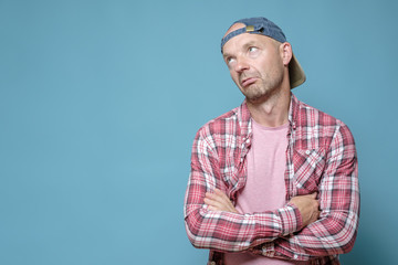 Offended, upset man stands with crossed arms and looks up. Copy space. 