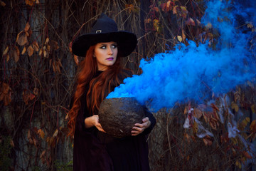 a girl in a black dress and a witch hat for Halloween with a VAT and blue smoke on a background of yellow and red leaves