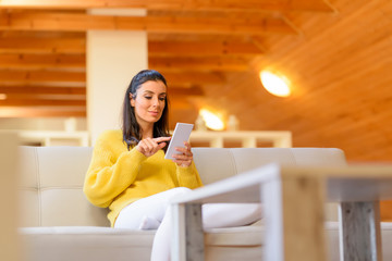 Portrait of a beautiful woman using her smartphone in the living