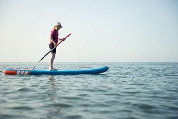 Happy teen girl paddling on sup board in Baltic sea