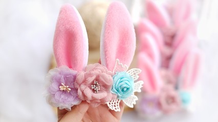 Obraz na płótnie Canvas Handmade flowers as headband hair accessory with bunny or rabbit ears as decoration in soft pastel colors