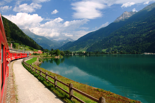 Switzerland - July 2012: Swiss Mountain Red Train Bernina Express at Lake of Poschiavo.