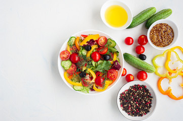 Vegetarian salad of colorful vegetables and ingredients of which it consists on a white concrete background. Copy space.