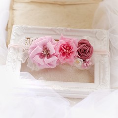 Handmade flower as headband hair accessory made out of fabric flowers in beautiful pastel colors place on vintage white photo frame