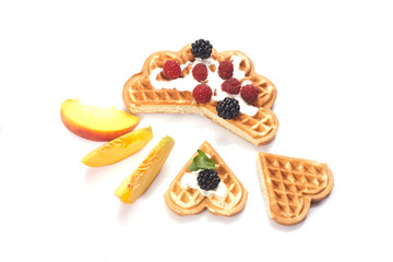 Waffles with berries and peaches isolated on white background
