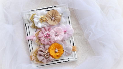 Handmade flower as headband hair accessory made out of fabric flowers in beautiful pastel colors place on vintage white photo frame