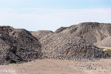 Industrial background with pile of gravel in front of the sky. Extraction of gravel. Construction of roads. Piles of gravel on construction site. Morning. Beautiful light.