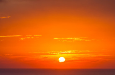 Brilliant orange-red clouds reflected into the ocean in a beautiful sunset