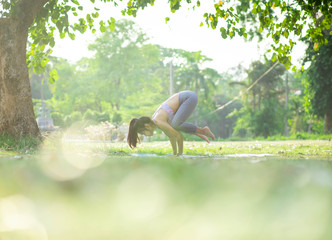 Young asian woman doing yoga under the tree in park