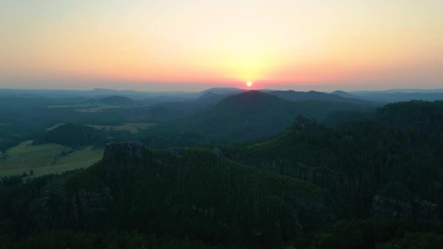 Luftaufnahme Sonnenuntergang in sch&ouml;ner Landschaft mit W&auml;ldern, Wiesen und H&uuml;tte auf Fels in Natur im Elbsandsteingebirge, S&auml;chsische Schweiz