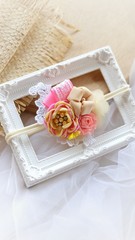 Handmade flower headband hair accessory made out of fabric flowers in beautiful pastel colors on vintage white photo frame