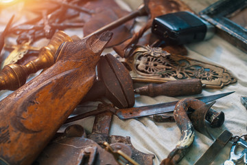 Broken wooden butt of a rifle, rusty metal parts, brass candelabra on countertop at antique bazaar....