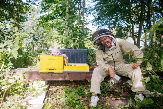Portrait of a female beekeeper, sitting next to her bee hive, la