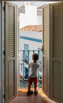Little kid looking at the street from a balcony