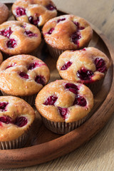 Freshly baked jam glazed cherry muffins on wooden tray. 