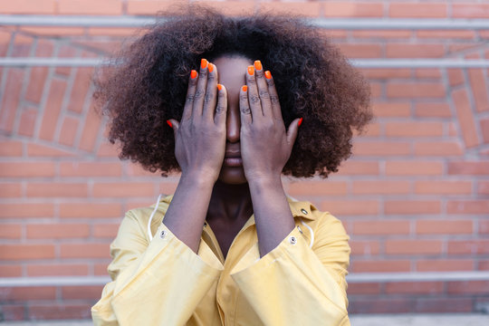 Street lifestyle closeup of black african american woman hands covering and hiding her face