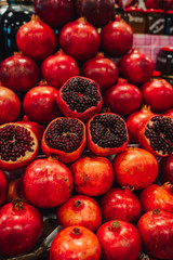 Juicy and ripe pomegranate with peel taken off, exposing fresh seeds, laying on pile of pomegranates