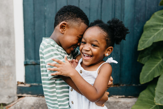 Two African American kids / brother and sister hugging.
