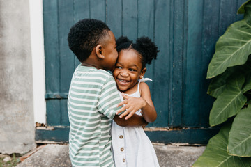 Two African American kids / brother and sister hugging.