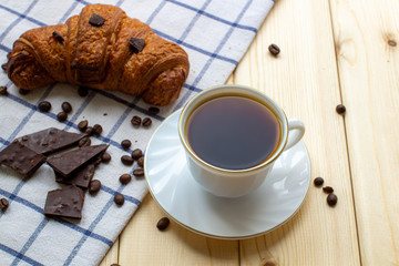 Coffee and a croissant on a wooden background. Visa from above