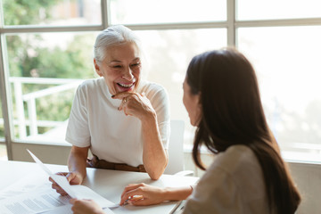 Cheerful mature manager discussing papers with coworker