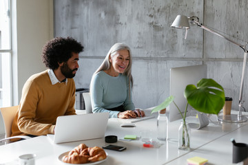 Multiracial coworkers using laptop and computer in office
