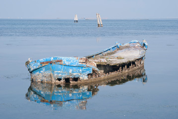 

shipwrecked and abandoned wooden boat in the middle of the water