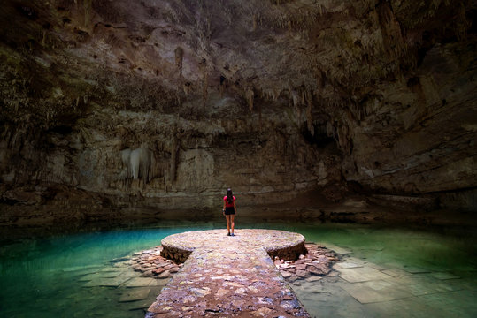 Woman standing in the middle of a lake in a cave