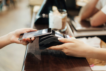 the client pays off at the cash desk through the terminal by phone. close-up