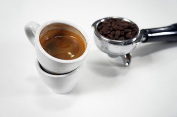 A portafilter with coffee beans, a portafilter with ground coffee, an espresso shot and an empty cup of espresso shot