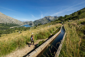 Fototapeta na wymiar escursionista andando junto a la canal de transvase del Gorg Blau - Cúber, Escorca, Paraje natural de la Serra de Tramuntana, Mallorca, balearic islands, Spain