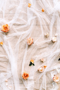 flat lay with roses and white chiffon fabric on wooden floor background