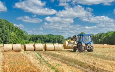 straw in round bales and a tractor in the field