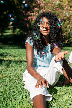 beautiful black teenager girl trying to catch soap bubbles