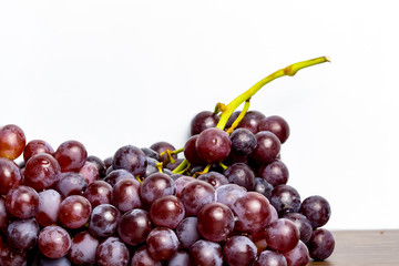 Close-up of red seedless grapes with water droplets on a white background.