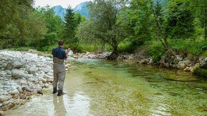 Fototapeta na wymiar A man fly fishing on the alpine Soca River near Tolmin, Slovenia